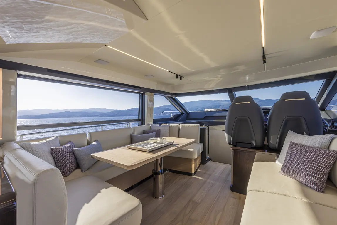 Luxurious yacht interior featuring spacious seating, a dining table, and panoramic sea views through large windows.